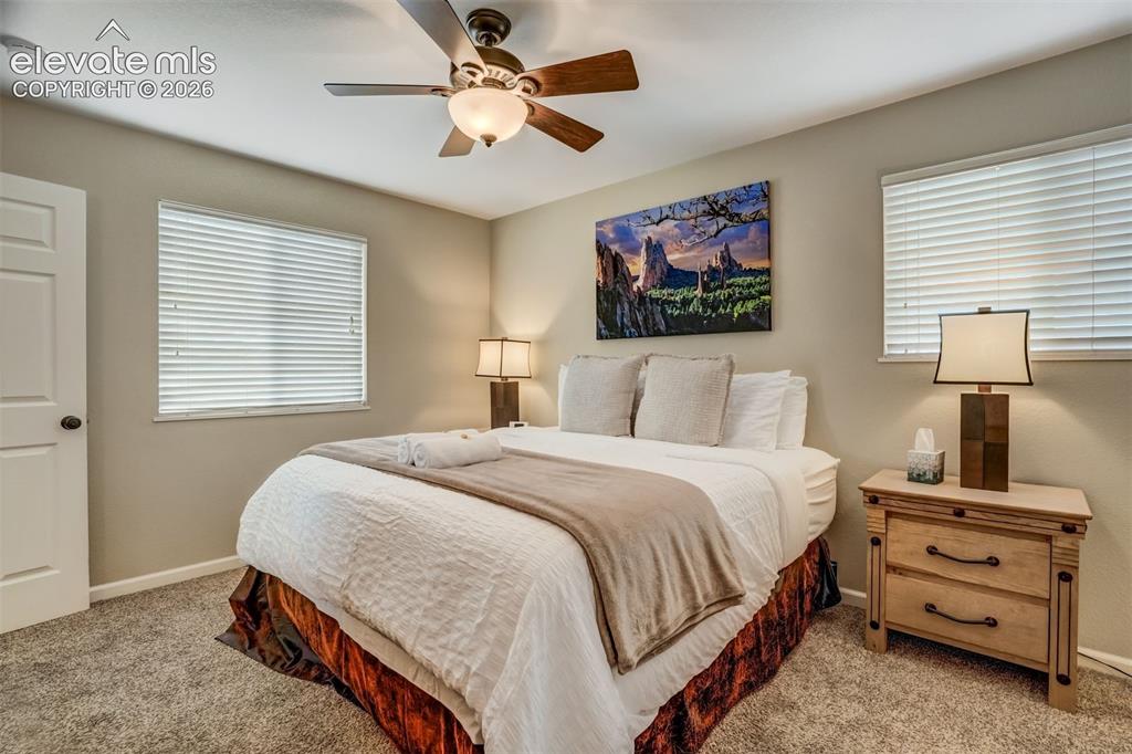 Image 26 of 50: Carpeted flooring, ceiling fan with integrated lighting, two windows with b
