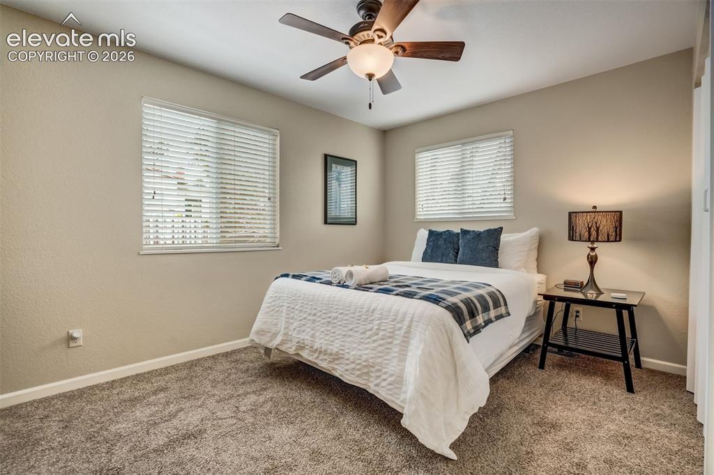 Image 33 of 50: Textured wall finish, ceiling fan with light fixture, two windows with blin