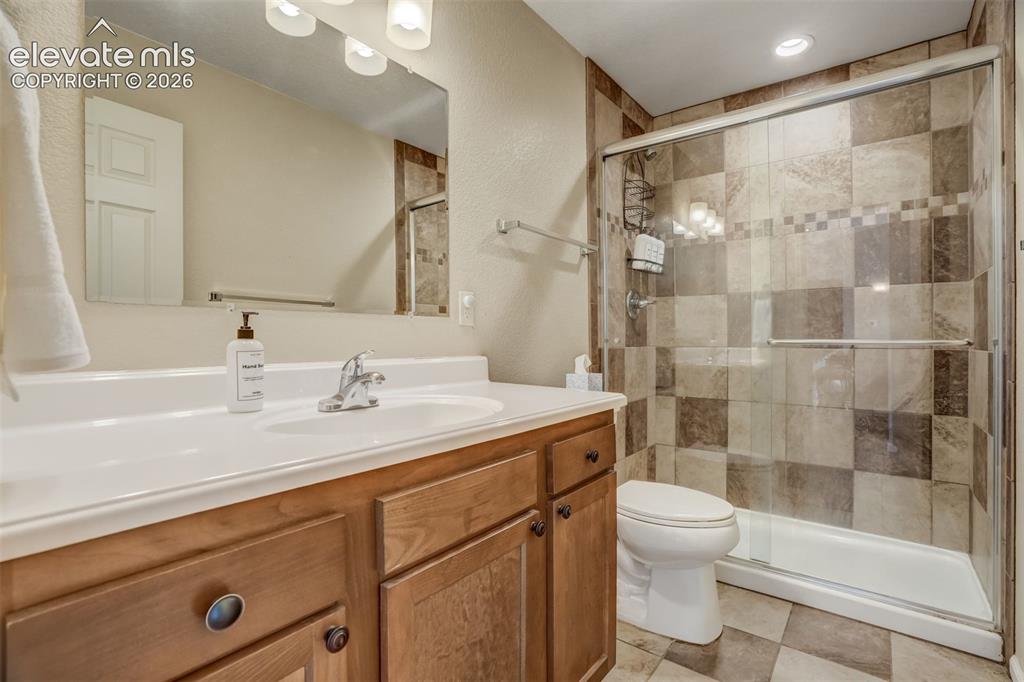 Image 37 of 50: Vanity with wood-finish cabinetry, integrated sink, and chrome faucet