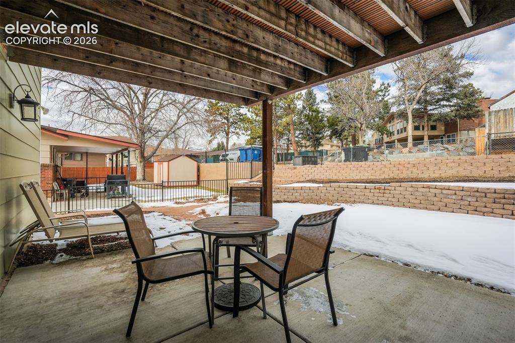 Image 41 of 50: Covered patio featuring an exposed wood beam ceiling, concrete flooring, an