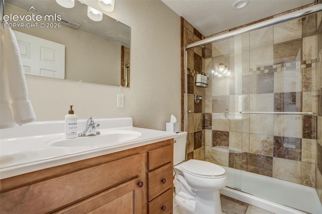 Image 42 of 50: Vanity with an integrated white sink, wood-finish cabinetry, and a chrome f