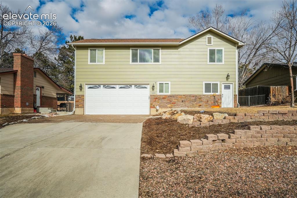 Image 5 of 50: Two-story exterior with light green siding and stone accents