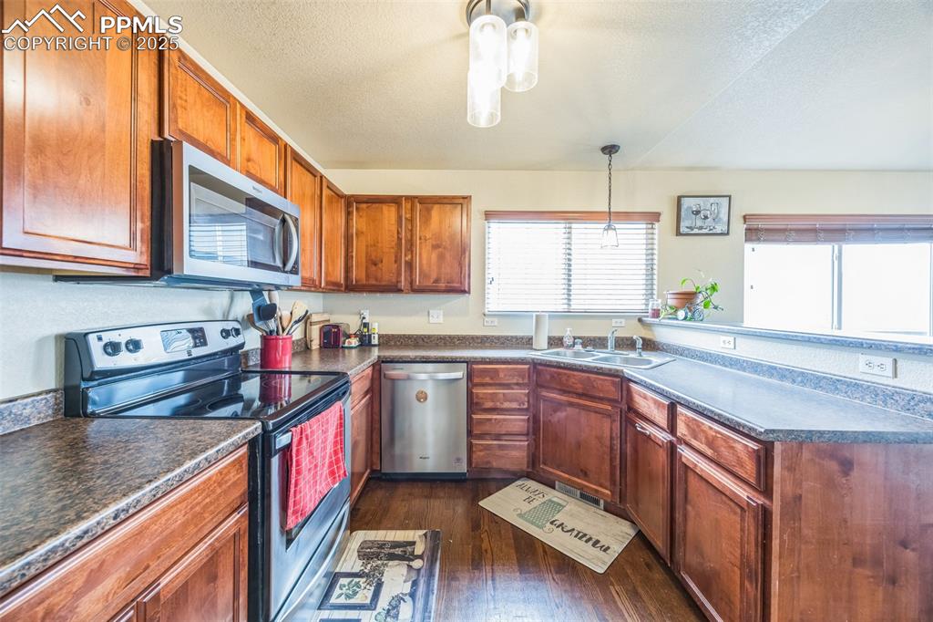 Image 9 of 29: Kitchen with dark wood-type flooring, a peninsula, appliances with stainles