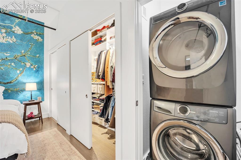 Image 11 of 48: Clothes washing area with light wood-type flooring and stacked washing mach