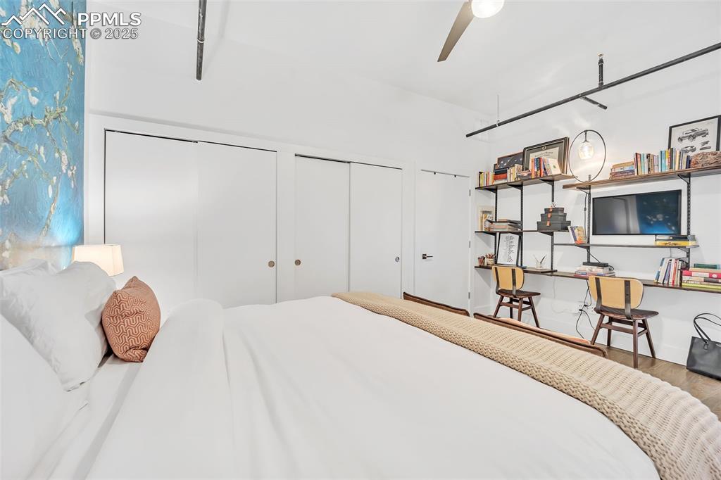 Image 13 of 48: Bedroom featuring a ceiling fan, two closets, and wood finished floors