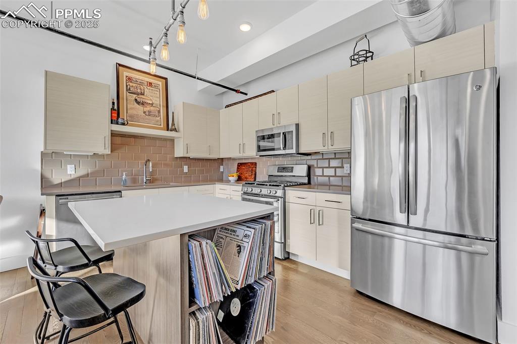 Image 19 of 48: Kitchen with hanging light fixtures, stainless steel appliances, cream cabi