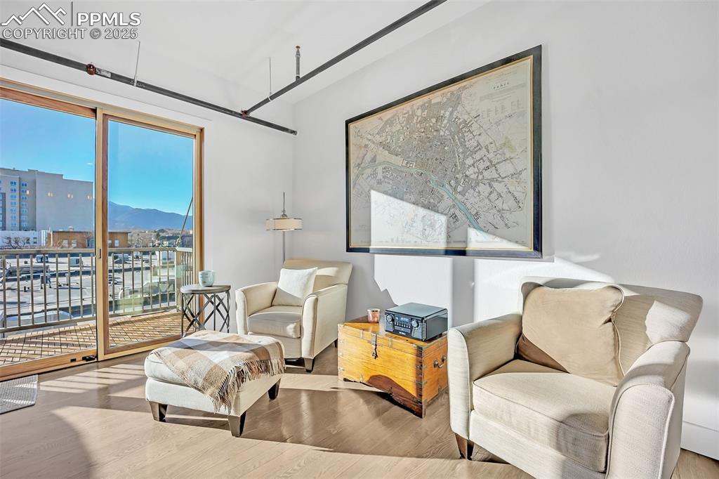 Image 27 of 48: Sitting room with light wood-style flooring, a mountain view, and a city vi
