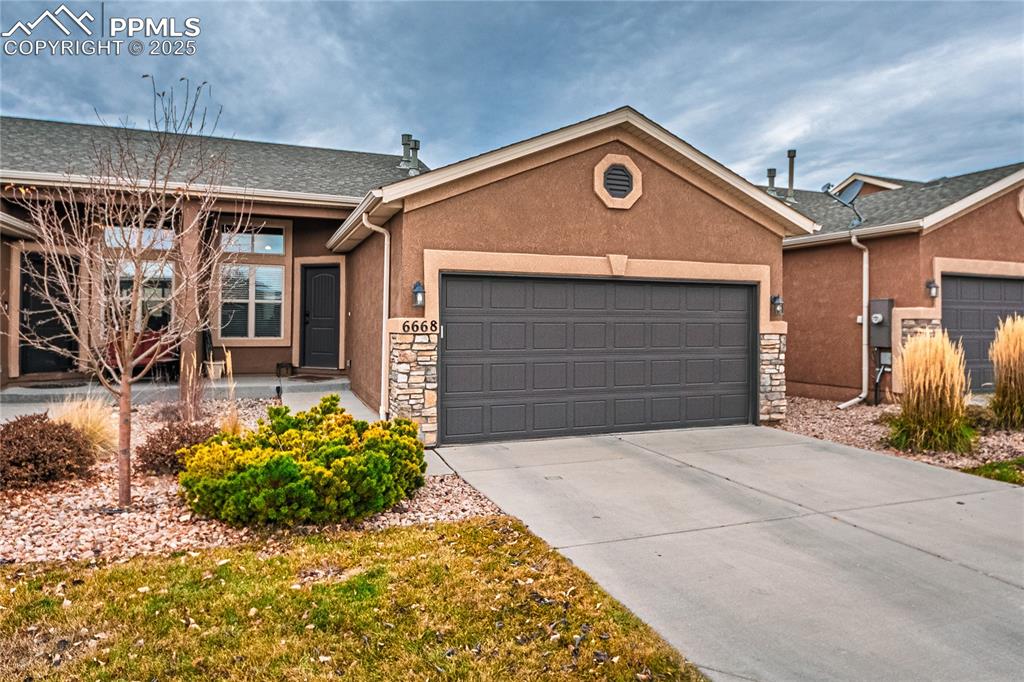 Caption: Ranch-style home with an attached garage, stucco siding, and stone siding