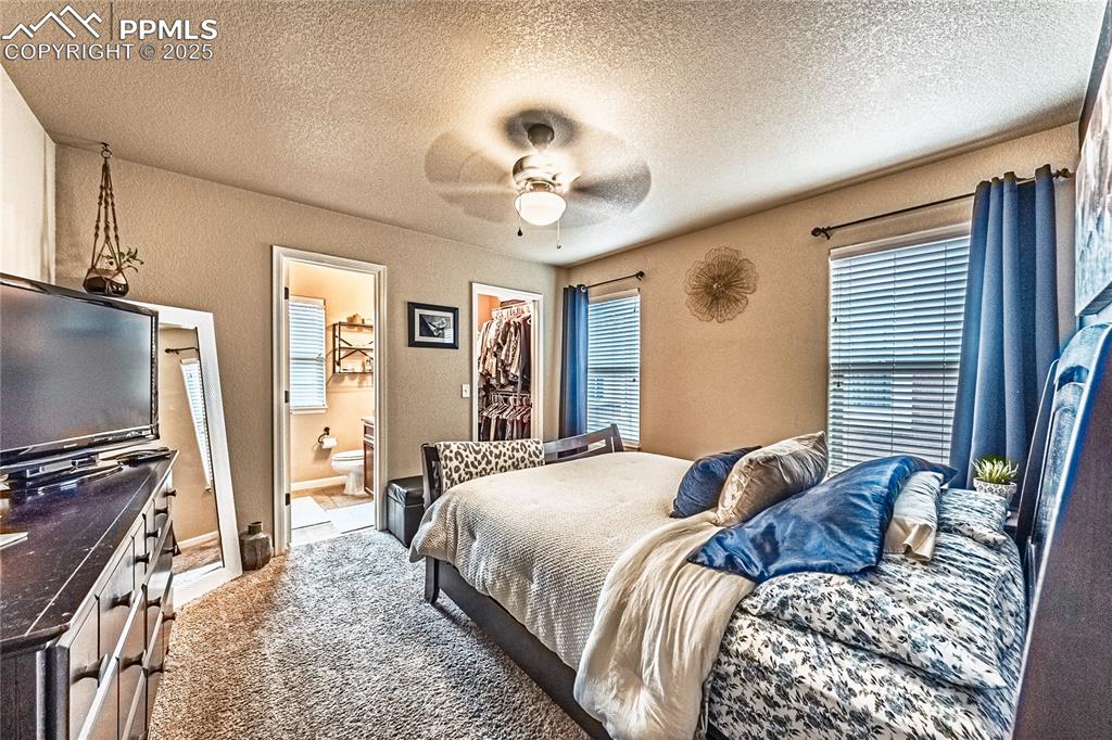Image 13 of 36: Carpeted bedroom featuring a textured ceiling, a walk in closet, a ceiling 