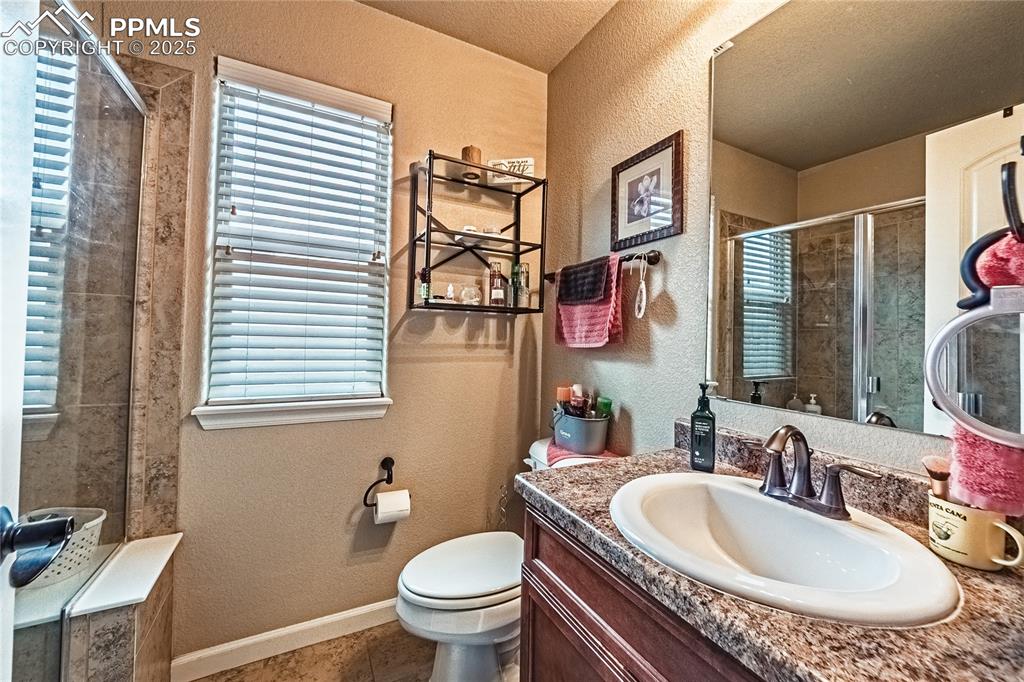 Image 16 of 36: Full bathroom with a textured wall, a stall shower, vanity, tile patterned 