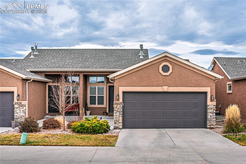 Image 2 of 36: Ranch-style home with stone siding, a shingled roof, stucco siding, an atta