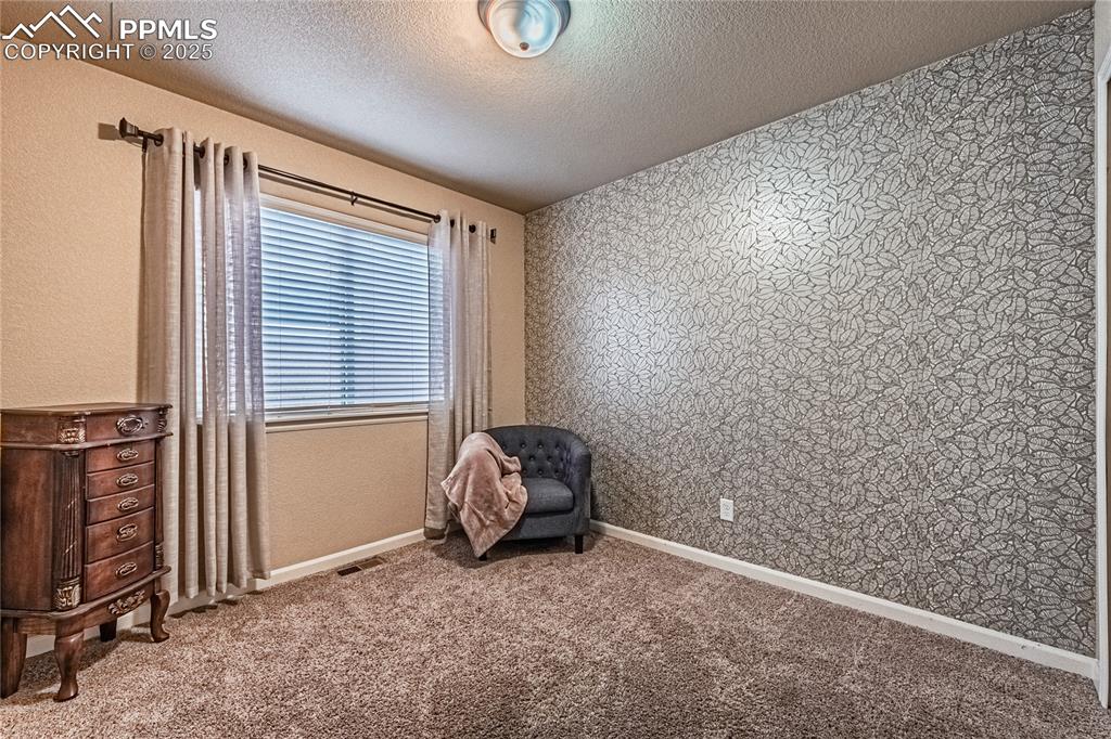 Image 21 of 36: Bedroom featuring a textured ceiling, carpet floors, wallpapered walls, and