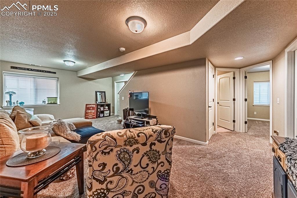 Image 23 of 36: Carpeted living area with a textured ceiling and baseboards