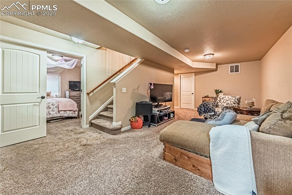 Image 25 of 36: Carpeted living room featuring stairway and a textured ceiling