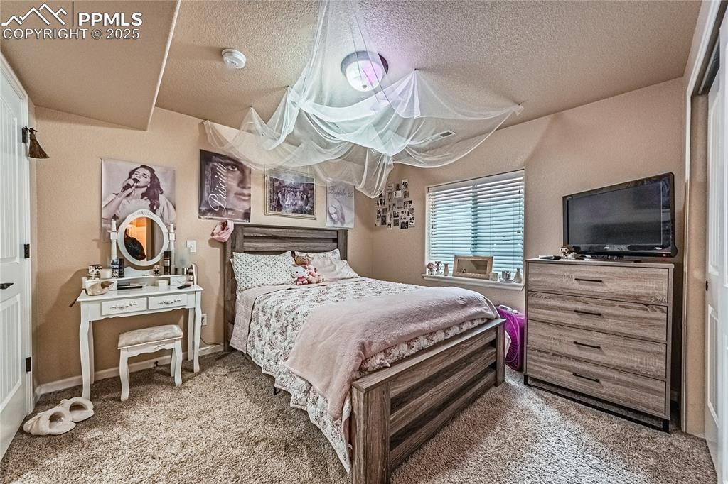 Image 26 of 36: Carpeted bedroom featuring a textured ceiling and baseboards