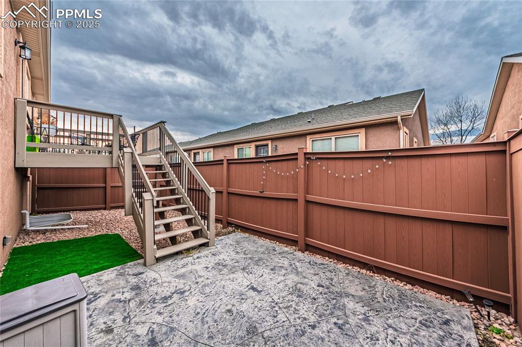 Image 32 of 36: Fenced backyard with a deck and stairway