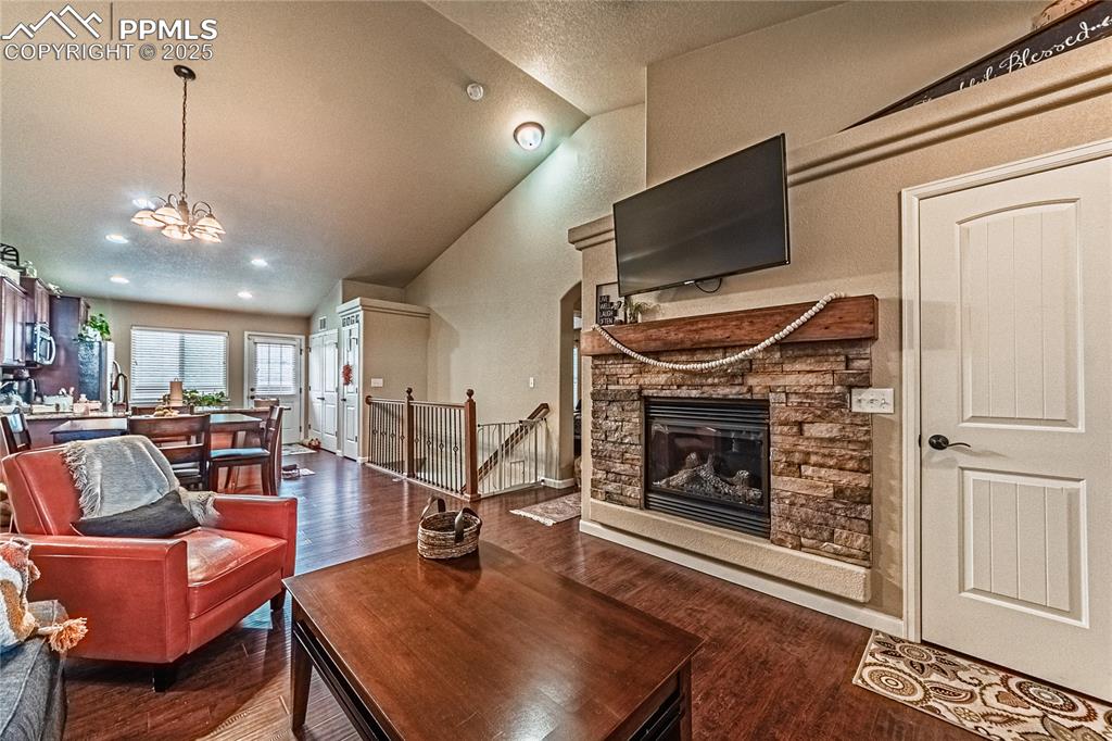 Image 5 of 36: Living area with a stone fireplace, dark wood-type flooring, high vaulted c