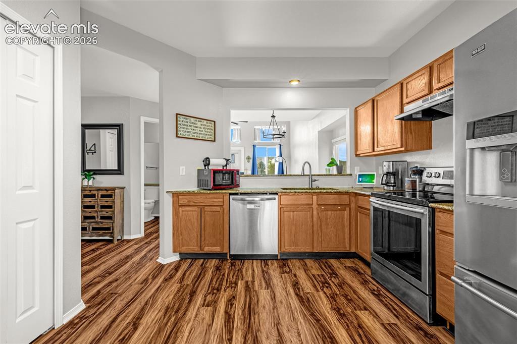 Image 11 of 42: Kitchen featuring wood-finish flooring, granite-style countertops, stainles