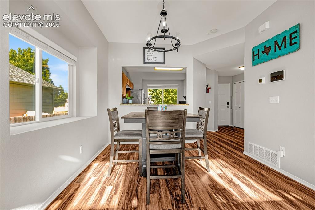 Image 12 of 42: Dining area featuring wood-finish flooring, a contemporary chandelier, and