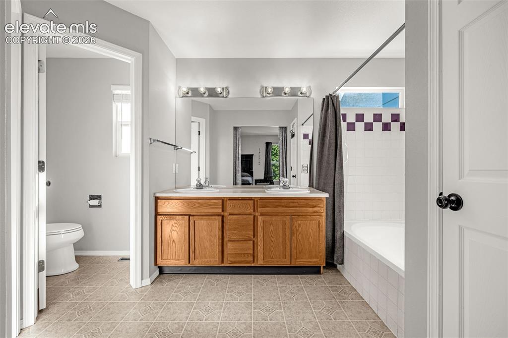 Image 17 of 42: Bathroom featuring a dual vanity with wood cabinetry and white sinks, a mir