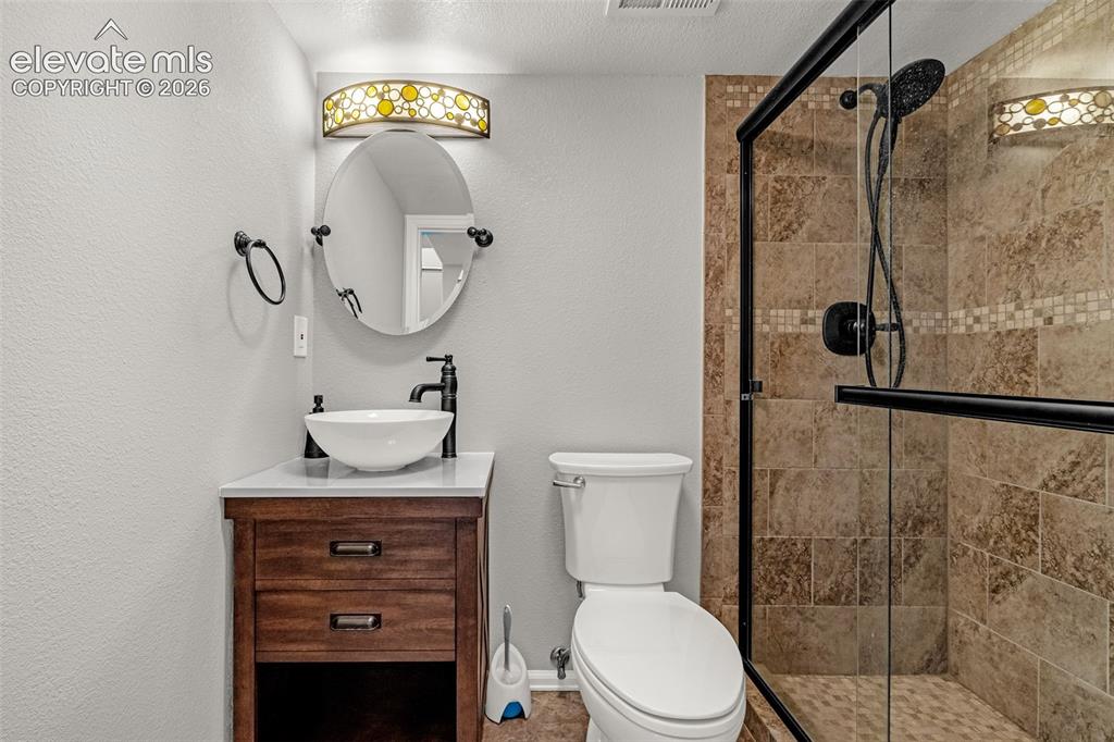 Image 26 of 42: Bathroom featuring a glass-enclosed shower with tiled walls and a rain show