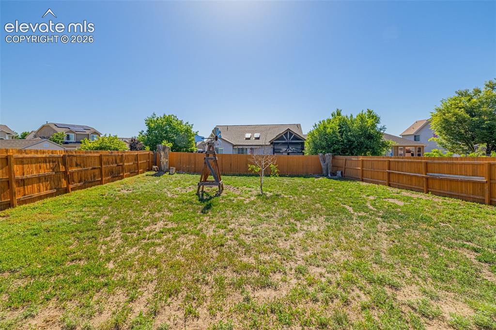 Image 29 of 42: Expansive backyard featuring a full wood privacy fence and a young tree