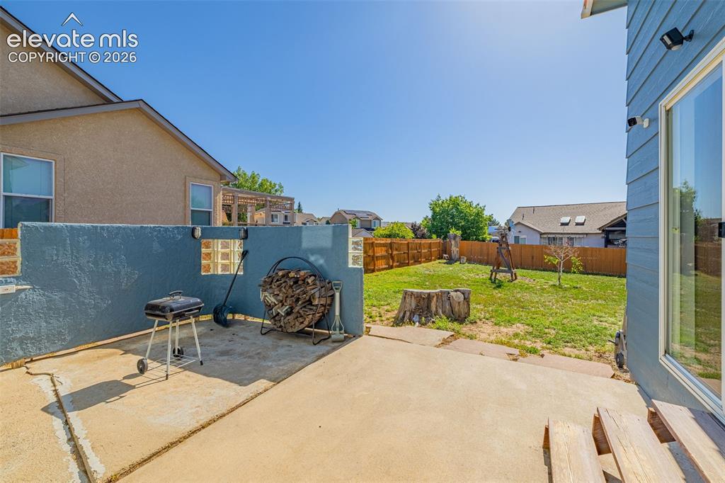 Image 30 of 42: Private backyard featuring a concrete patio, a stucco privacy wall with gla