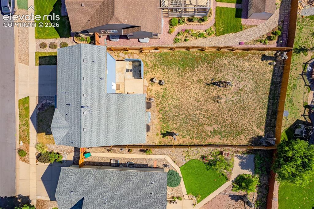 Image 33 of 42: Expansive backyard with a full perimeter fence, concrete patio, and mature