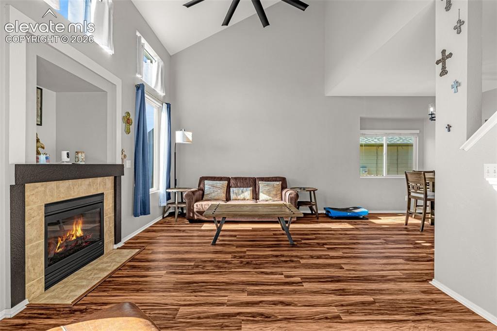 Image 7 of 42: Vaulted ceiling living space featuring a fireplace with a tiled surround an