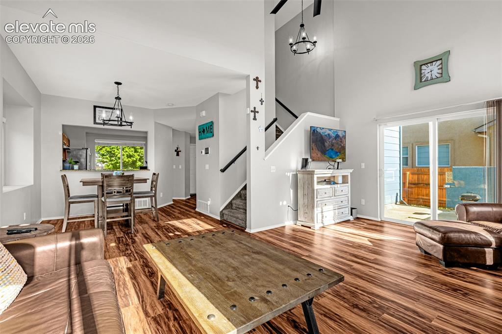 Image 8 of 42: Living area featuring wood-finish flooring, a double-height ceiling, and a