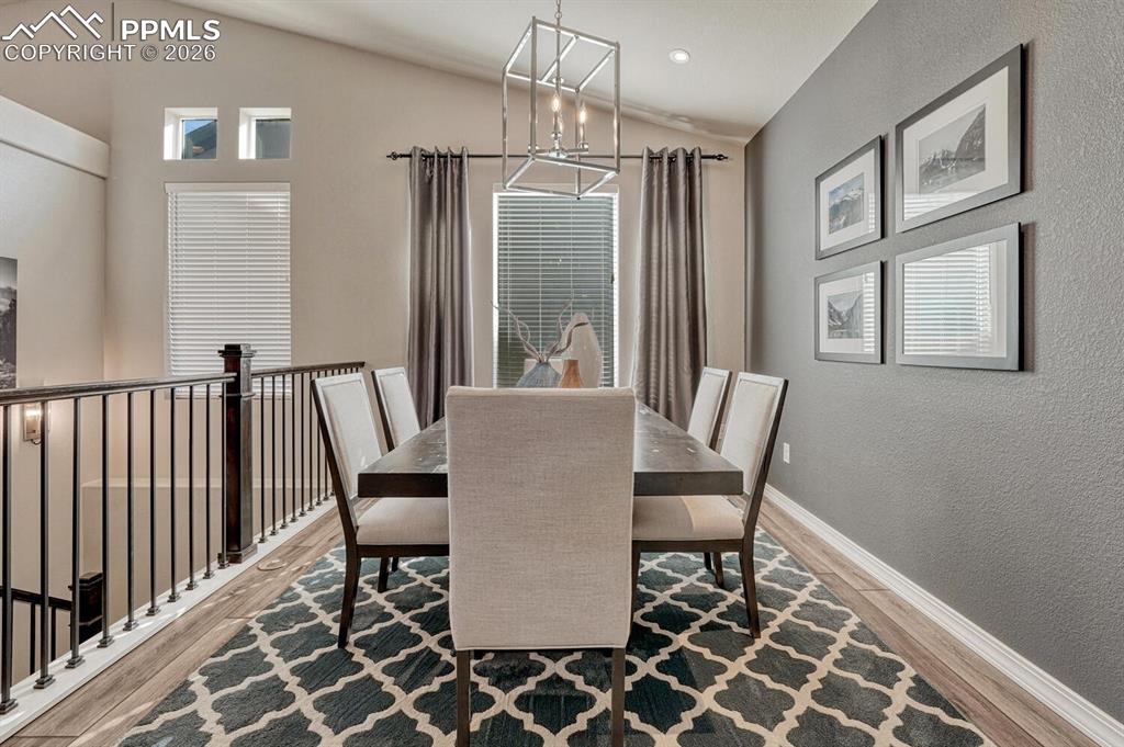 Image 12 of 50: Formal Dining Room with modern light fixture, accent wall, and large view w