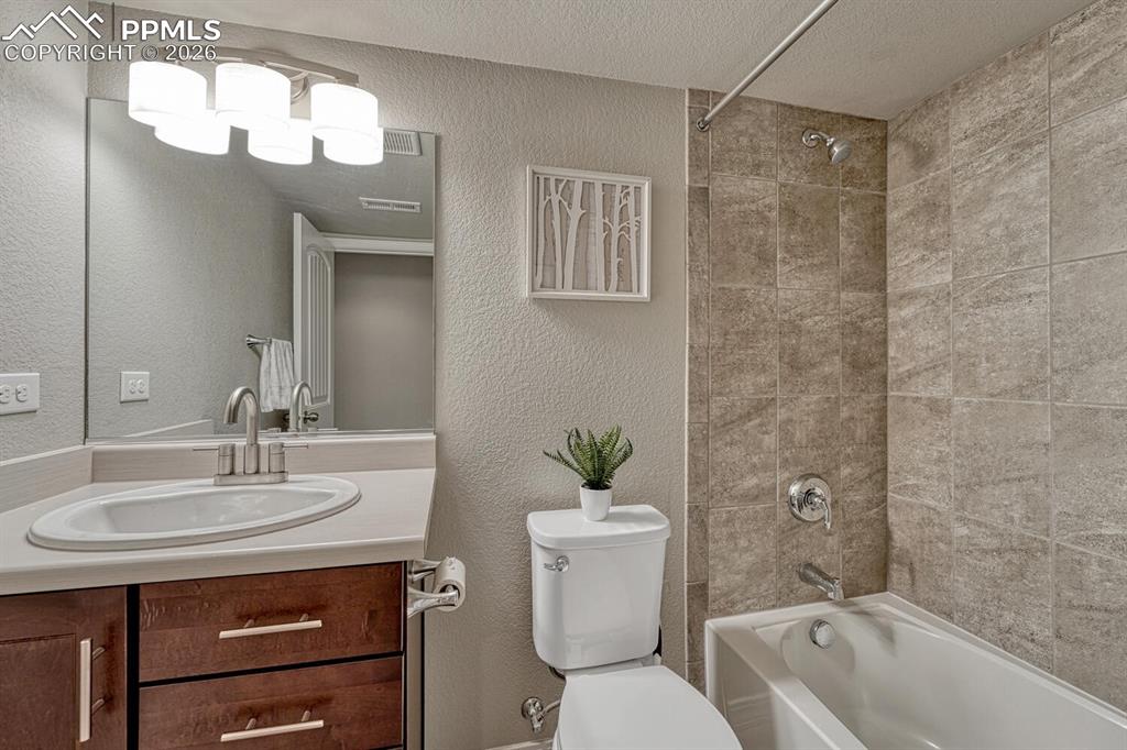 Image 39 of 50: Basement Full Bathroom with comfort height vanity, mirror, and tiled tub/sh