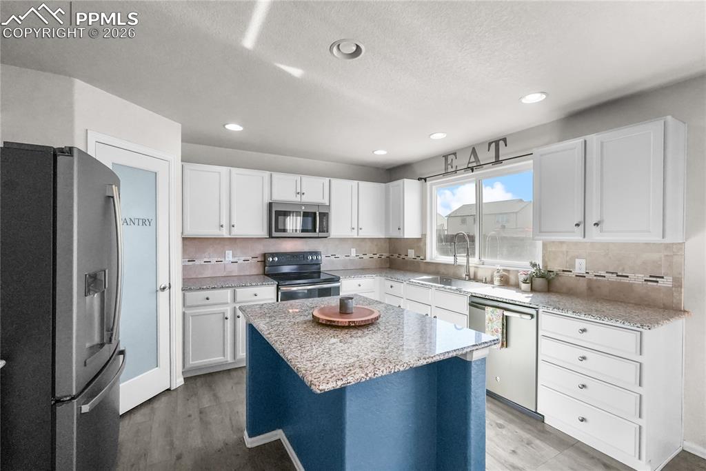 Image 10 of 25: Kitchen with granite countertops, island and pantry.