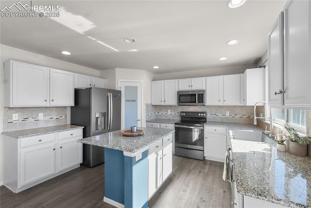 Image 8 of 25: Kitchen with granite countertops, island and pantry.