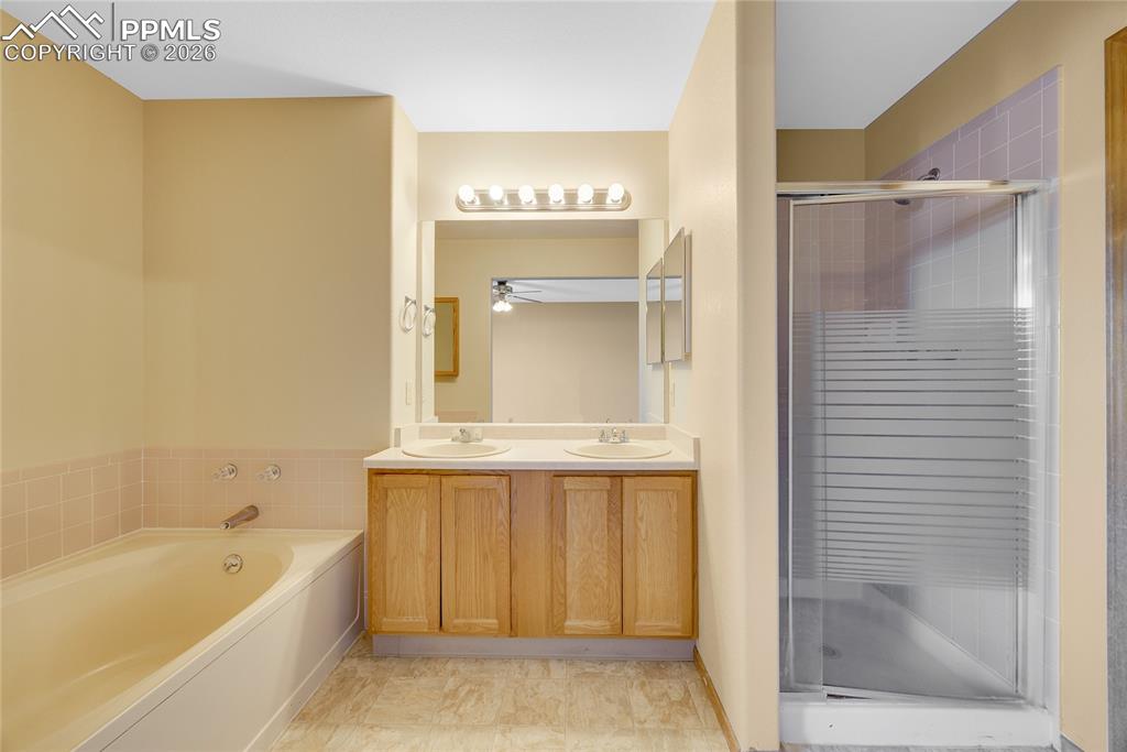Image 15 of 32: Full bathroom with a shower stall, double vanity, and a garden tub