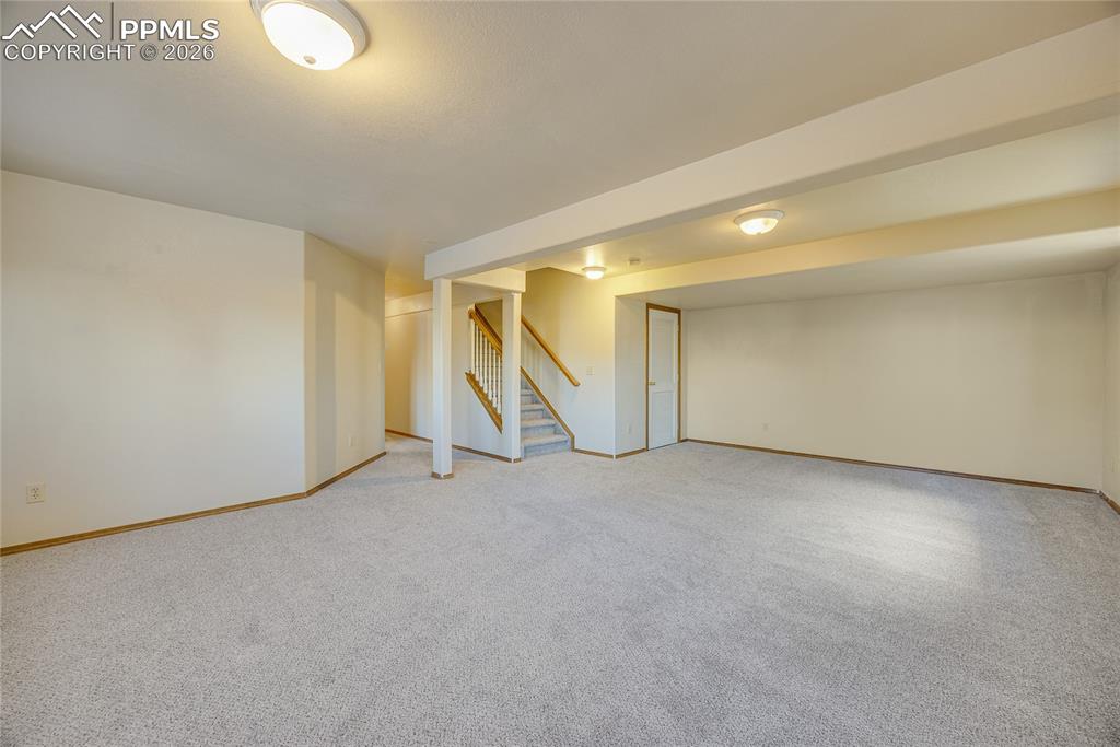 Image 22 of 32: Finished basement with stairway and light carpet