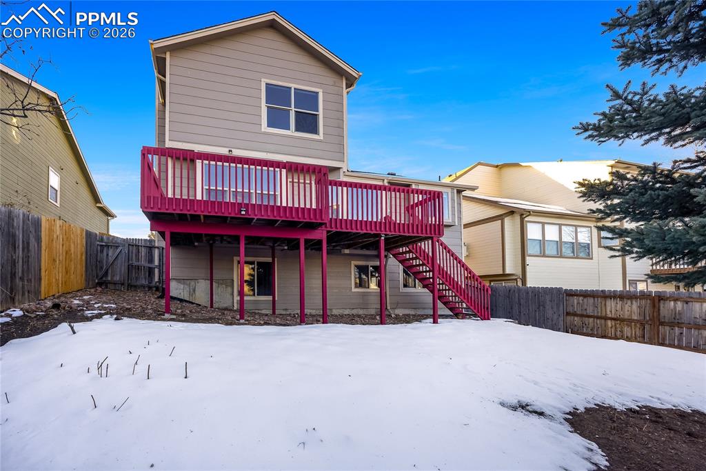Image 28 of 32: Snow covered rear of property with a fenced backyard, a wooden deck, stairw