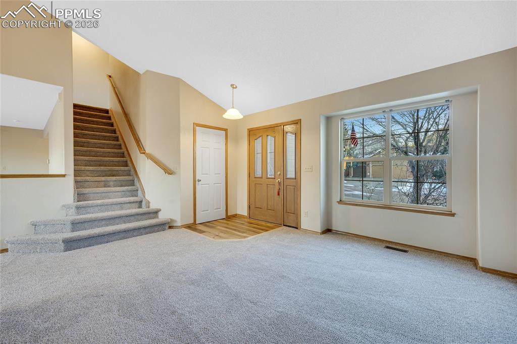 Image 4 of 32: Foyer featuring lofted ceiling, light carpet, and stairs