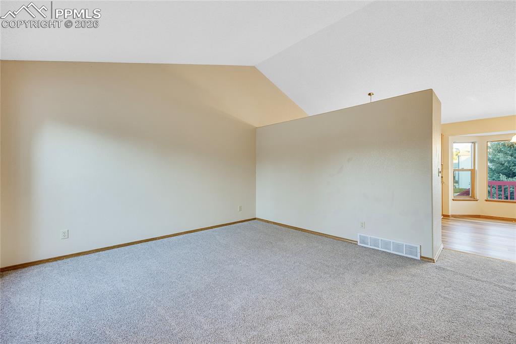 Image 5 of 32: Carpeted spare room featuring vaulted ceiling and baseboards
