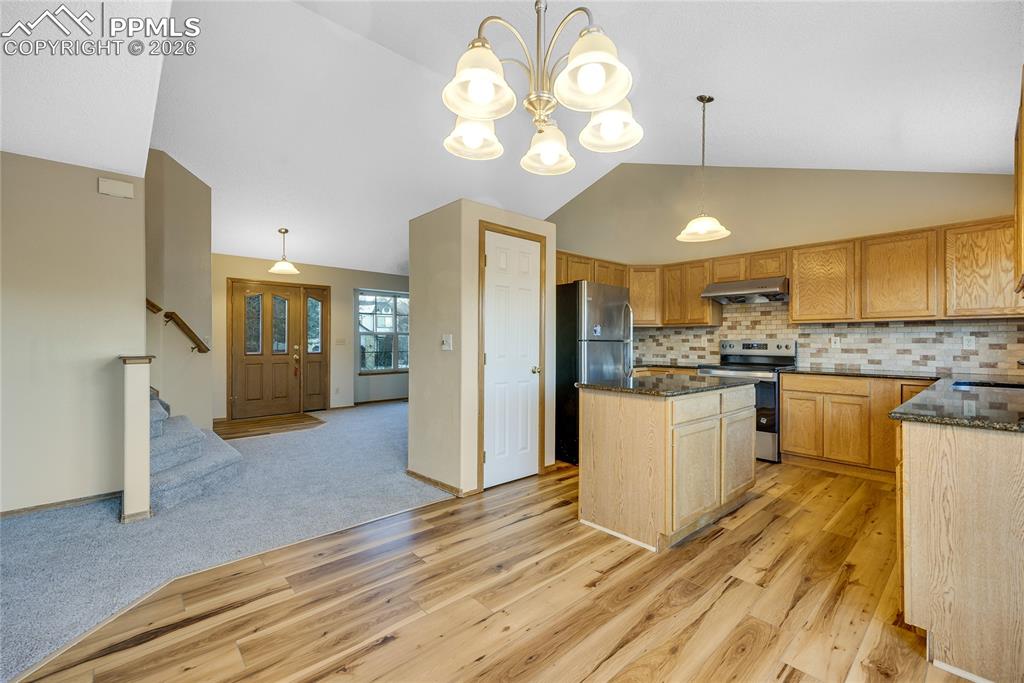 Image 6 of 32: Kitchen with lofted ceiling, appliances with stainless steel finishes, dark