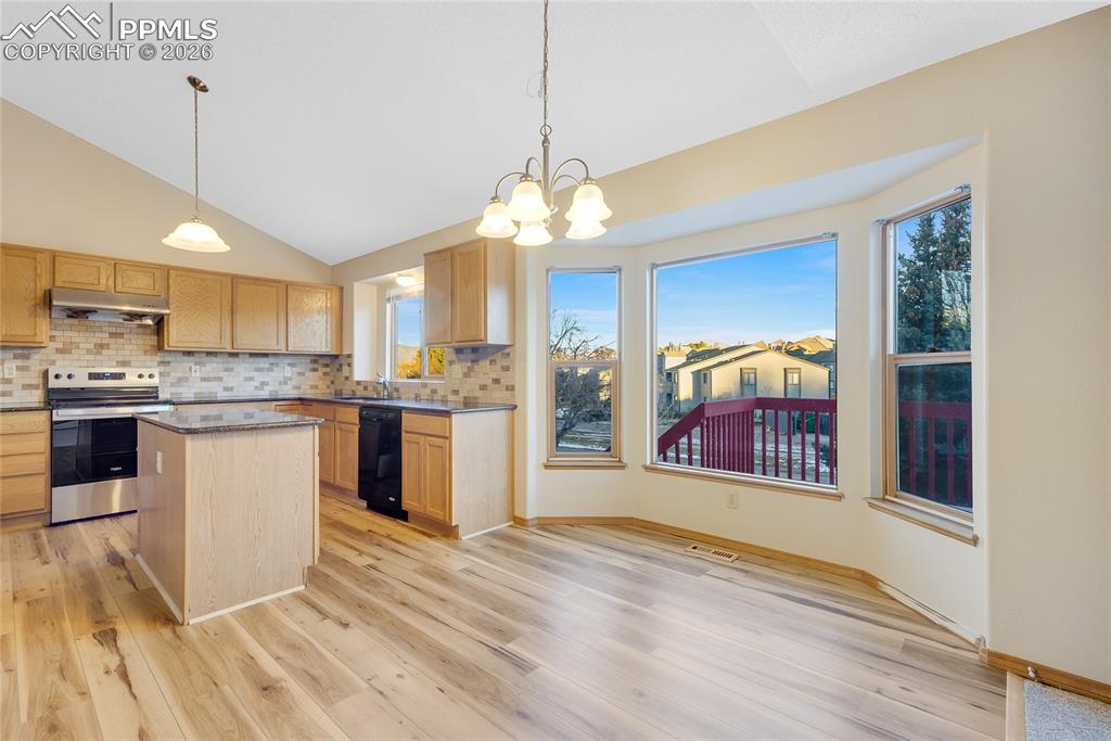 Image 7 of 32: Kitchen with pendant lighting, electric stove, a chandelier, decorative bac