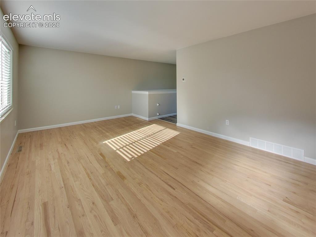 Image 12 of 32: Light wood-finish flooring, neutral wall tones, and white trim