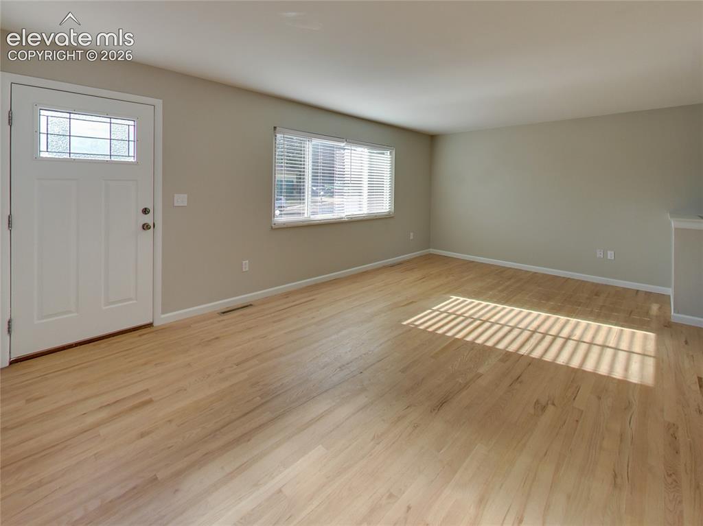 Image 13 of 32: Light wood-finish flooring, white door with decorative glass insert, window