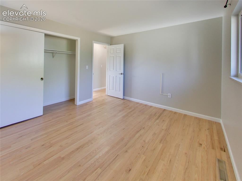 Image 15 of 32: Light wood-finish flooring, sliding closet doors, a paneled interior door,