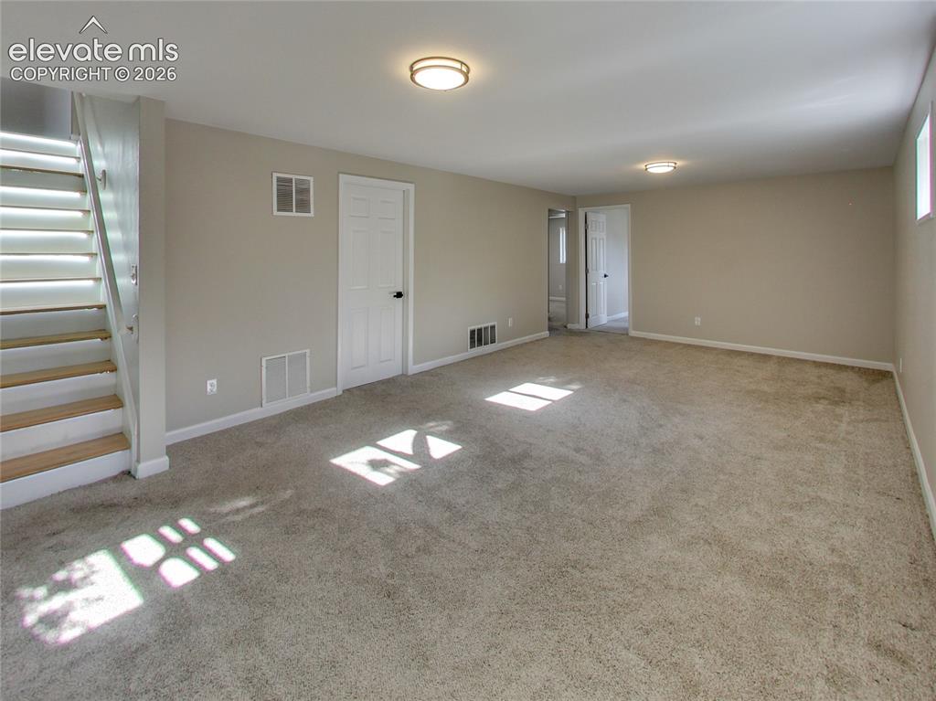 Image 20 of 32: Expansive carpeted room with neutral wall tones and white trim