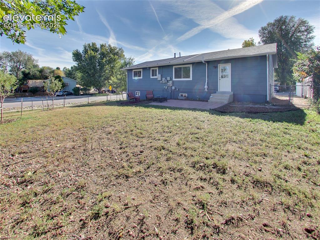 Image 30 of 32: Expansive backyard featuring a chain-link fence, a paved patio, and a direc
