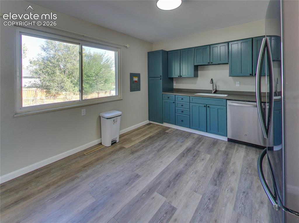 Image 7 of 32: Kitchen space featuring teal cabinetry, dark countertops, a stainless steel
