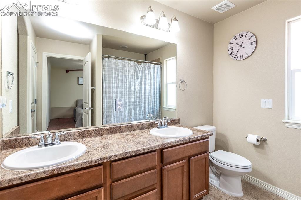 Image 16 of 33: Bathroom with double vanity and tile patterned flooring