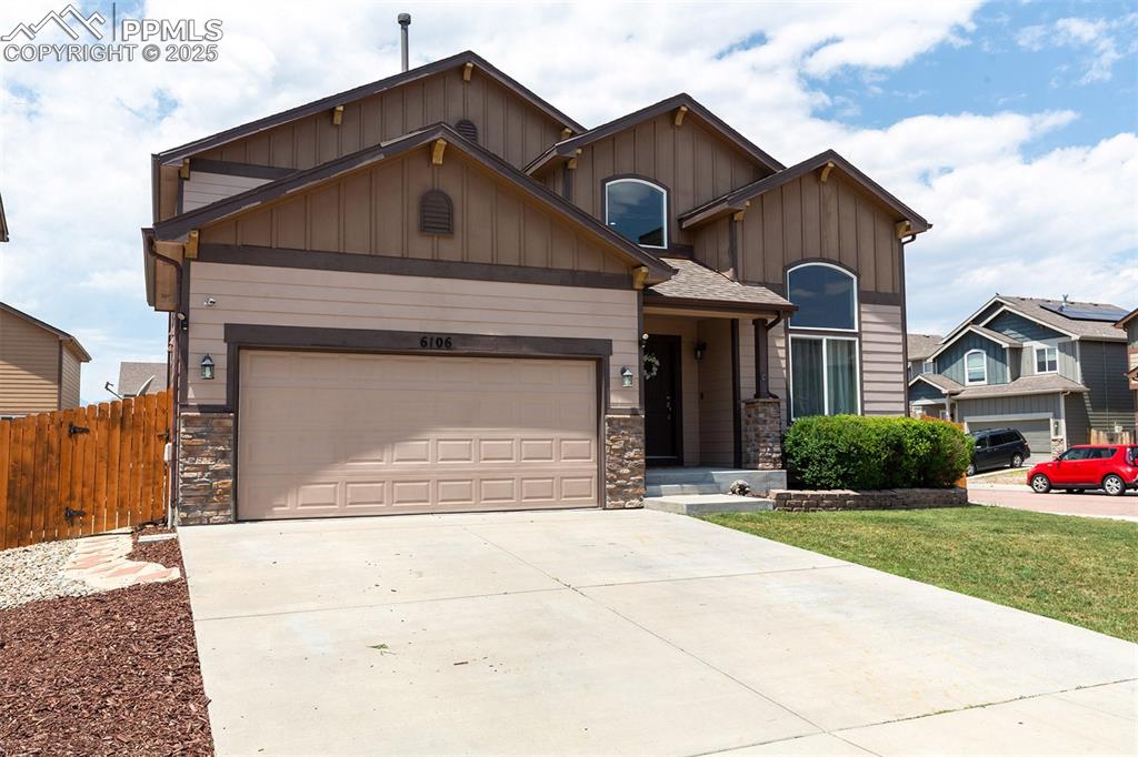 Image 2 of 33: Craftsman-style home with stone siding, board and batten siding, driveway,