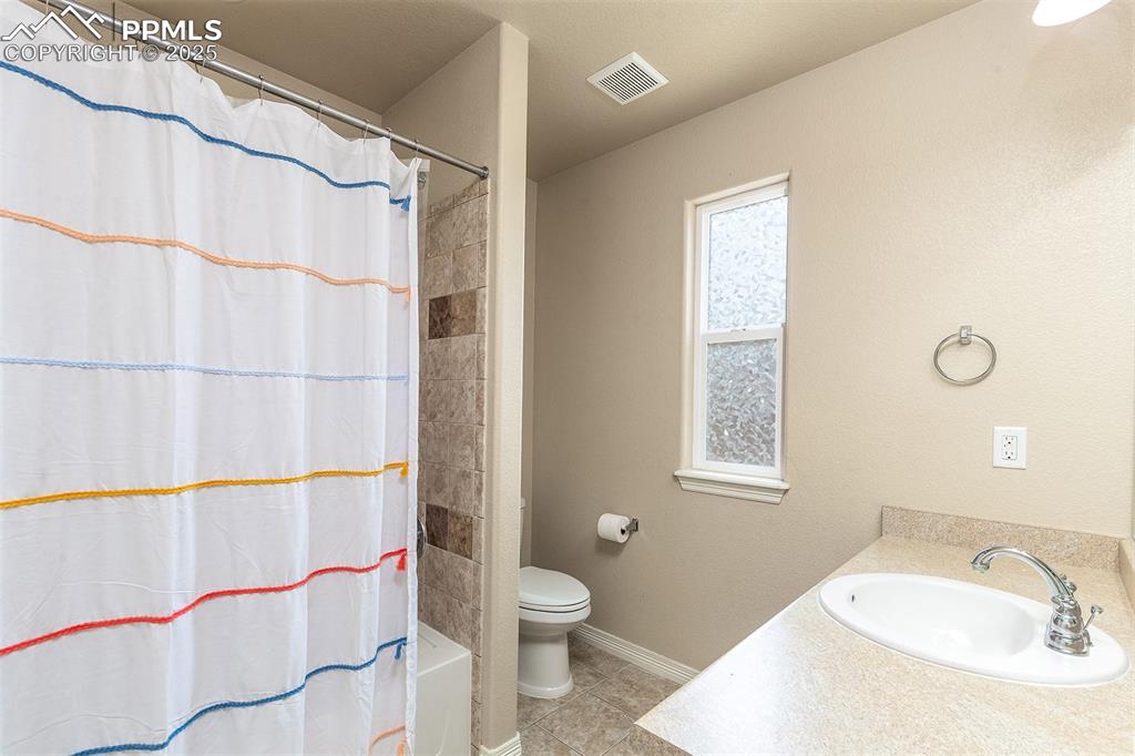 Image 22 of 33: Full bathroom with vanity, tile patterned flooring, and shower / tub combo
